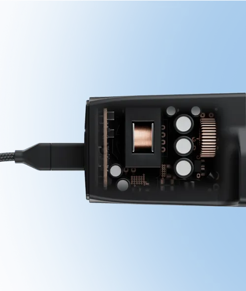 Close-up view of an electronic device with visible internal components including a copper coil, circuit board elements, and capacitors, against a blue background.