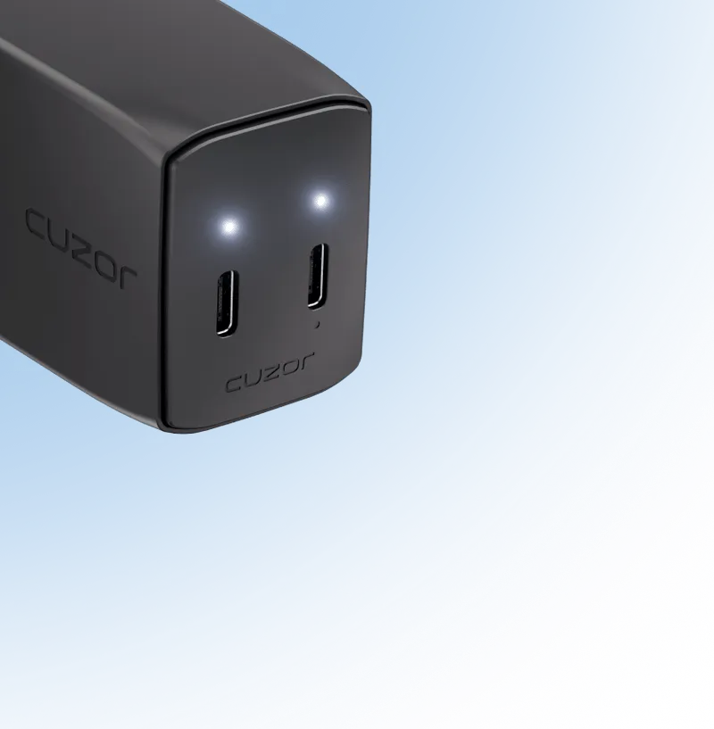Close-up of a black device with two illuminated USB-C ports labeled 'cuzor' on a light blue background.