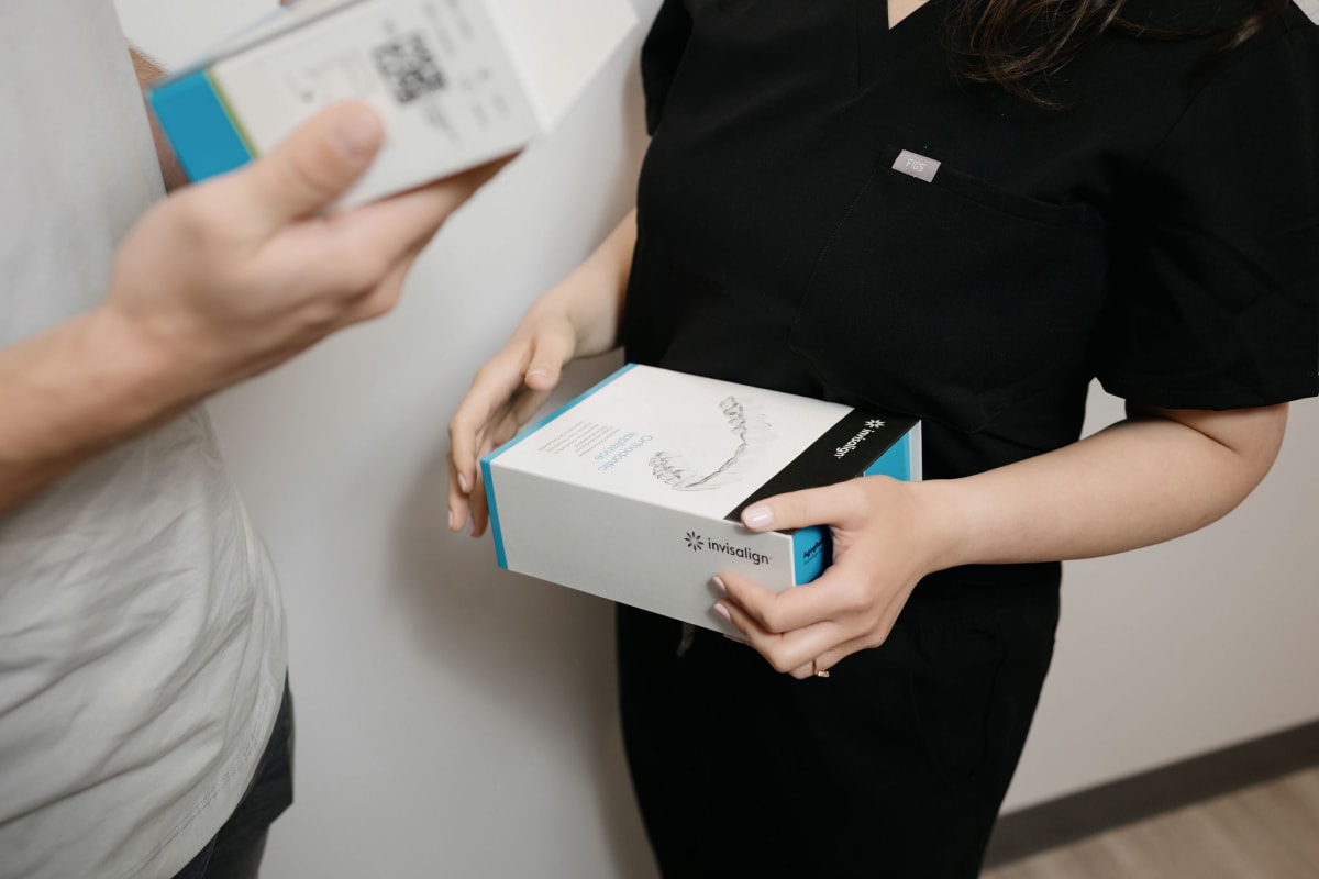 Patient receiving Invisalign clear aligners from dental professional at Genuine Smiles.
