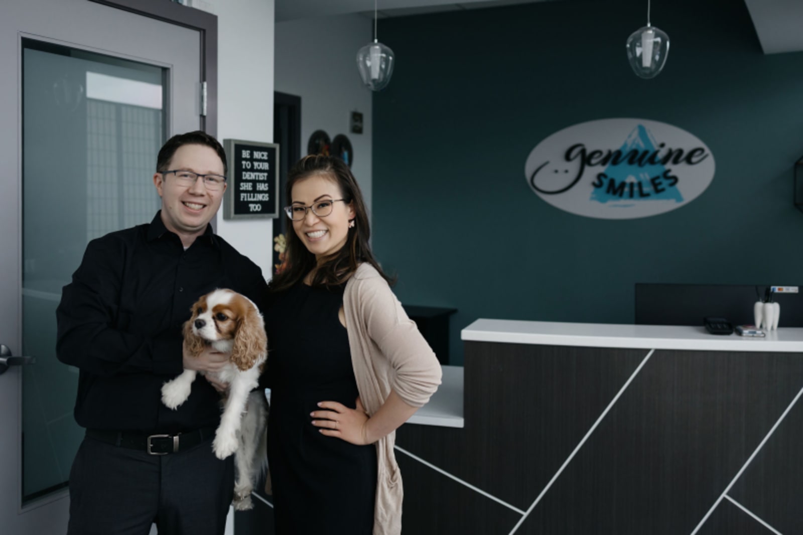Two dental professionals posing together in a modern dental office reception area at Genuine Smiles.