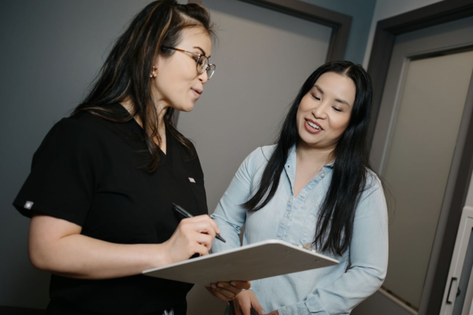 Two dental professionals reviewing treatment notes together in an office setting.