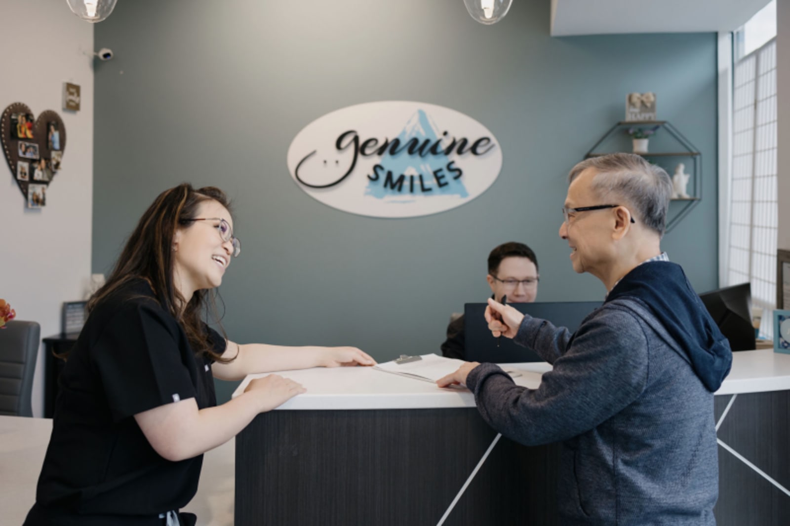 Friendly receptionist assisting a patient at the front desk of Genuine Smiles dental office.