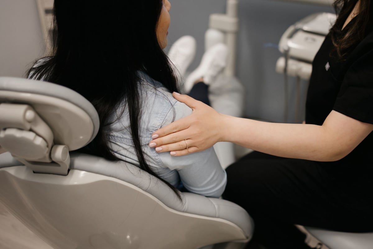 Dentist examining a patient's mouth in a dental chair at Genuine Smiles.