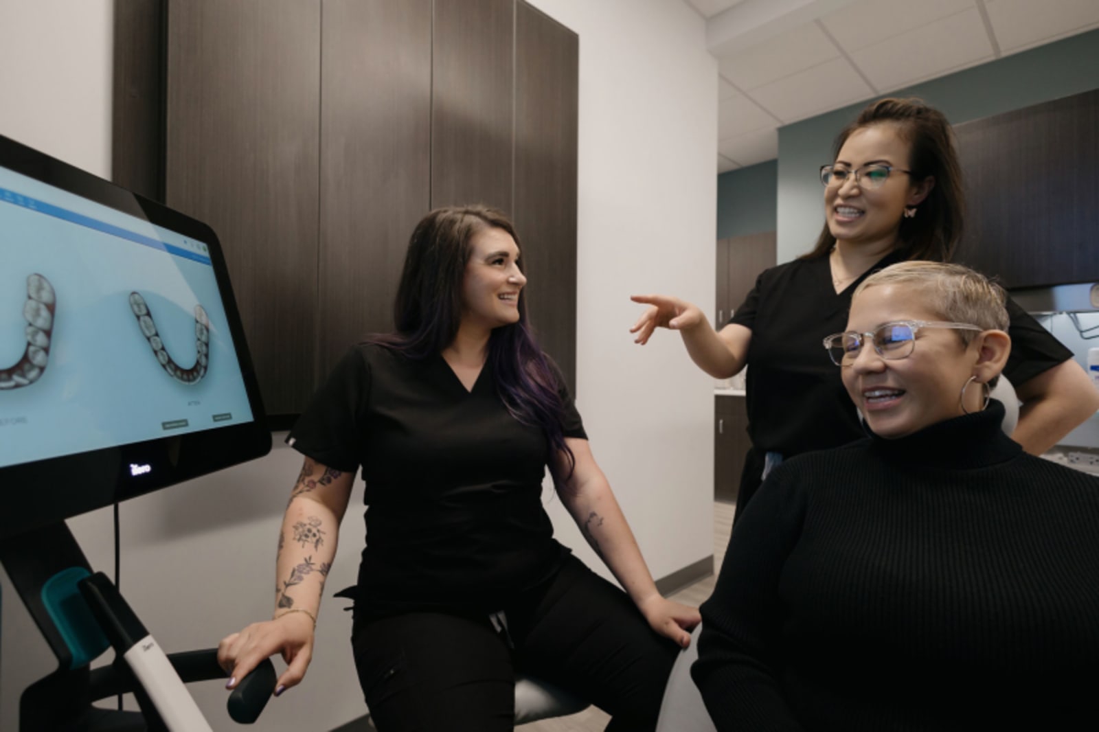 A female dentist discusses treatment options with a patient while reviewing digital imaging on a computer monitor.
