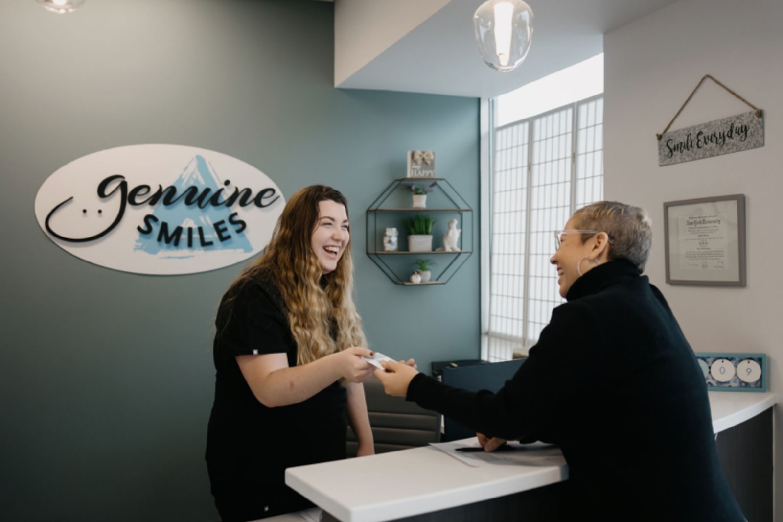 Female receptionist greeting patient at Genuine Smiles front desk in Everett dental office.