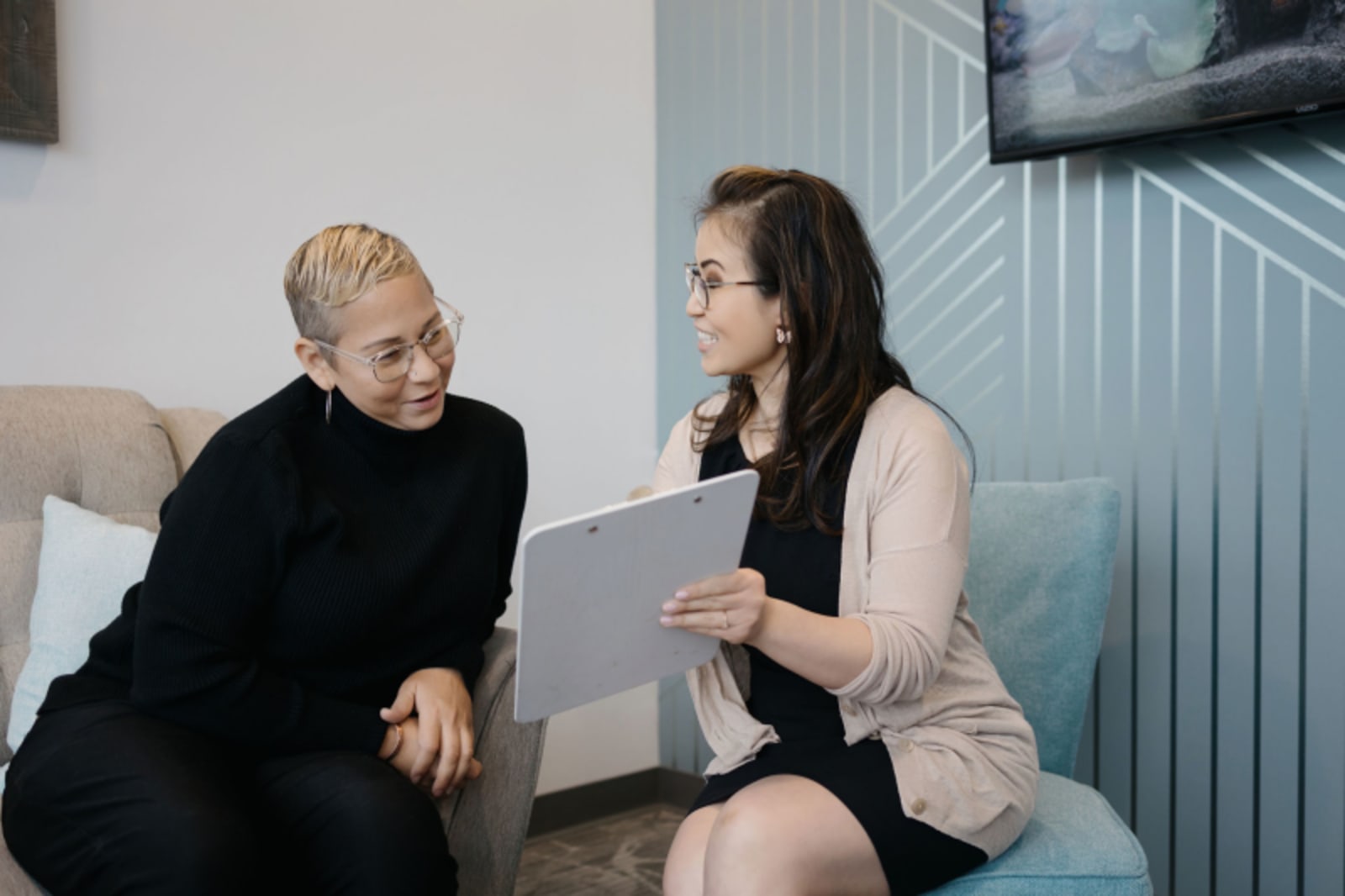 Two women having a consultation in a modern dental office waiting area.