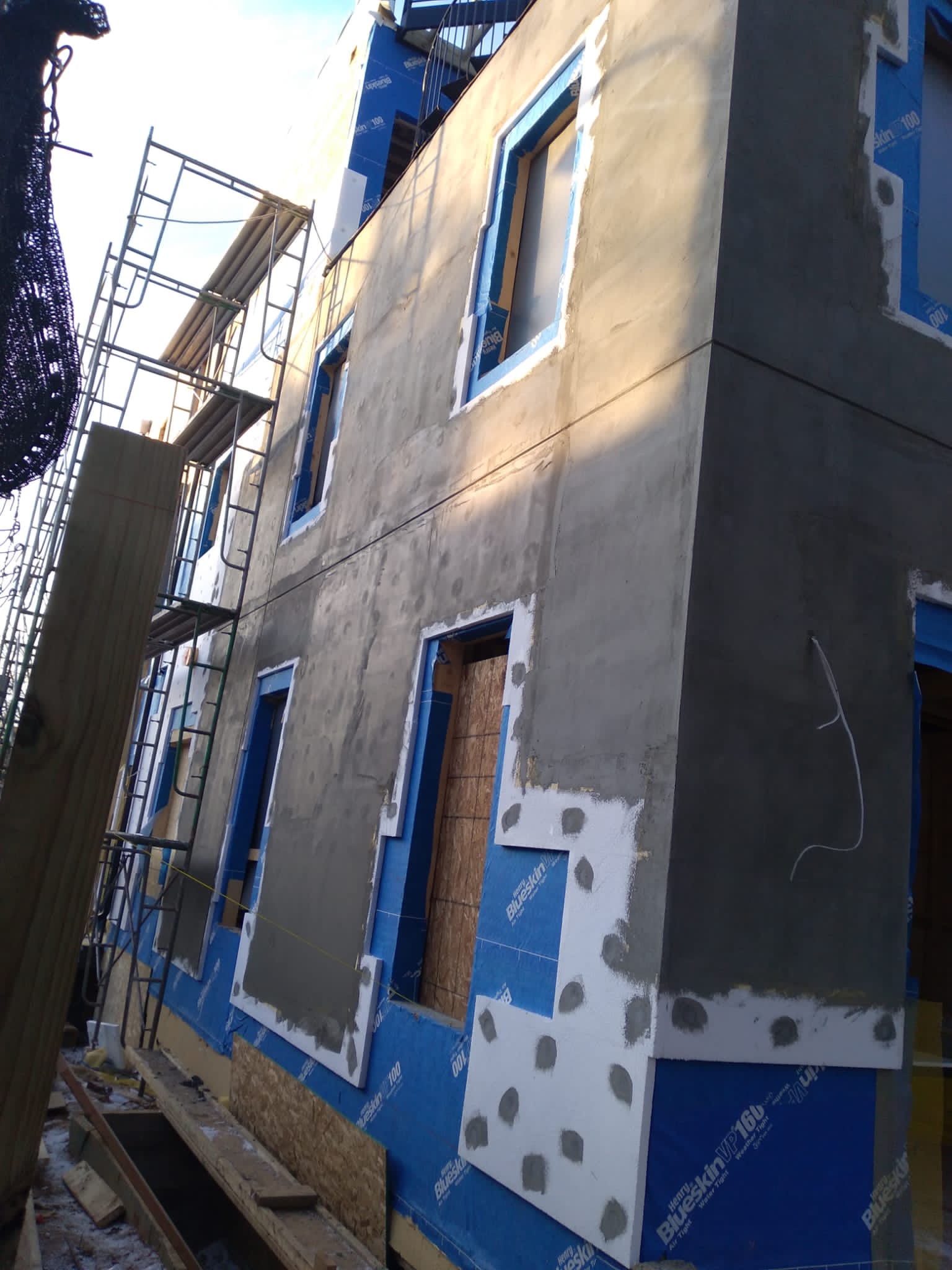Building under construction with scaffolding and partially installed exterior insulation and plaster.