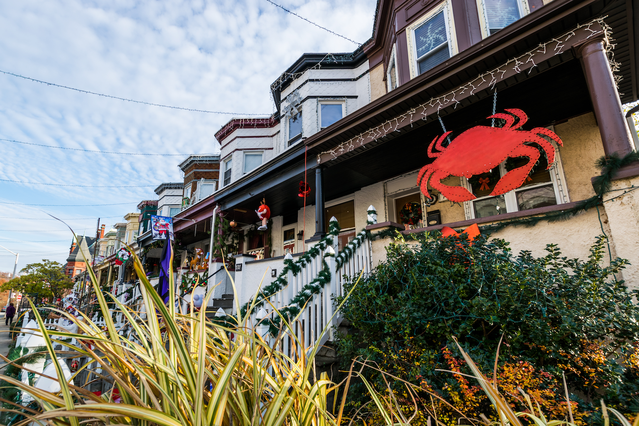 Row of decorated houses with festive garlands, Christmas lights, and a large red crab hanging on a porch.