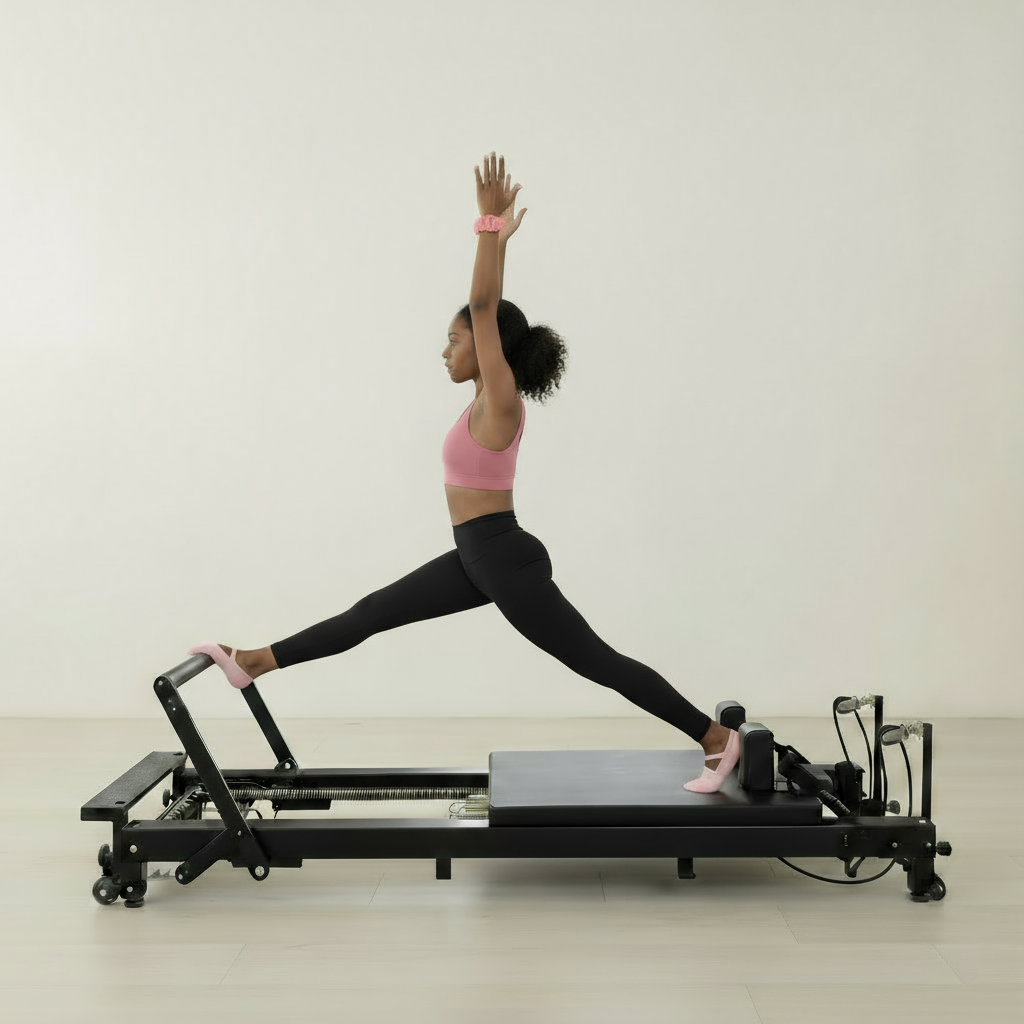 A woman in a pink sports outfit kneels on a black Pilates board, performing an upper-body resistance exercise with pull cords. She wears black grip socks for stability, and the scene is set against a beige minimalist background.
