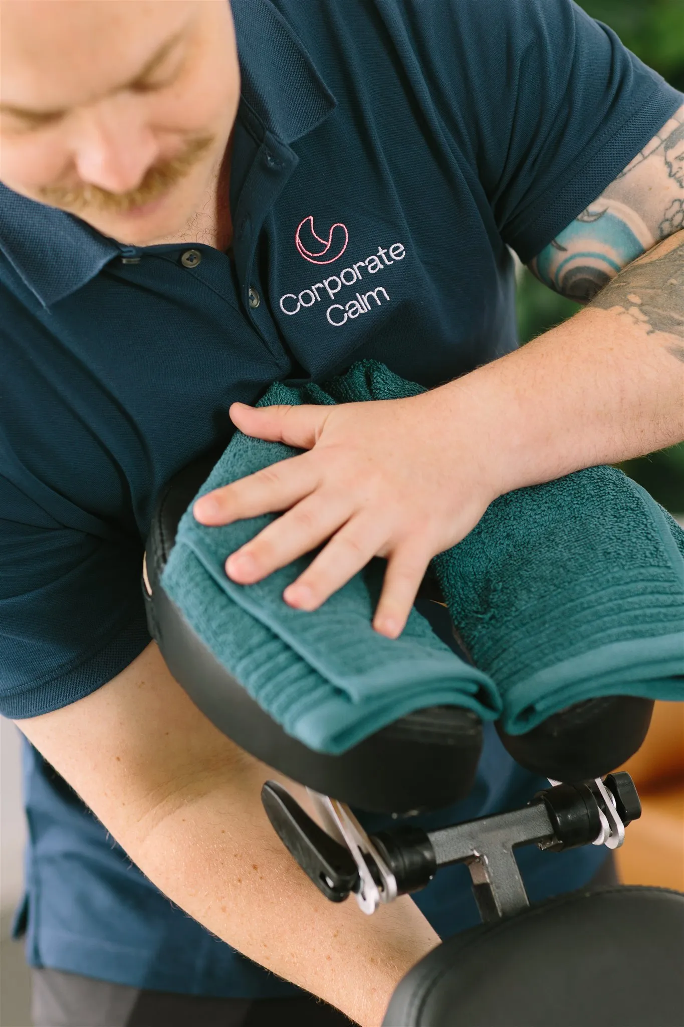 Corporate Calm therapist setting up portable event massage chair with green towels
