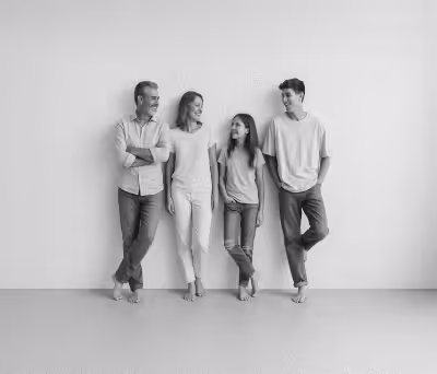 Imagem em tons de cinzo onde mostras qutro amigos encostados em uma parede branco sorrindo um para o outro