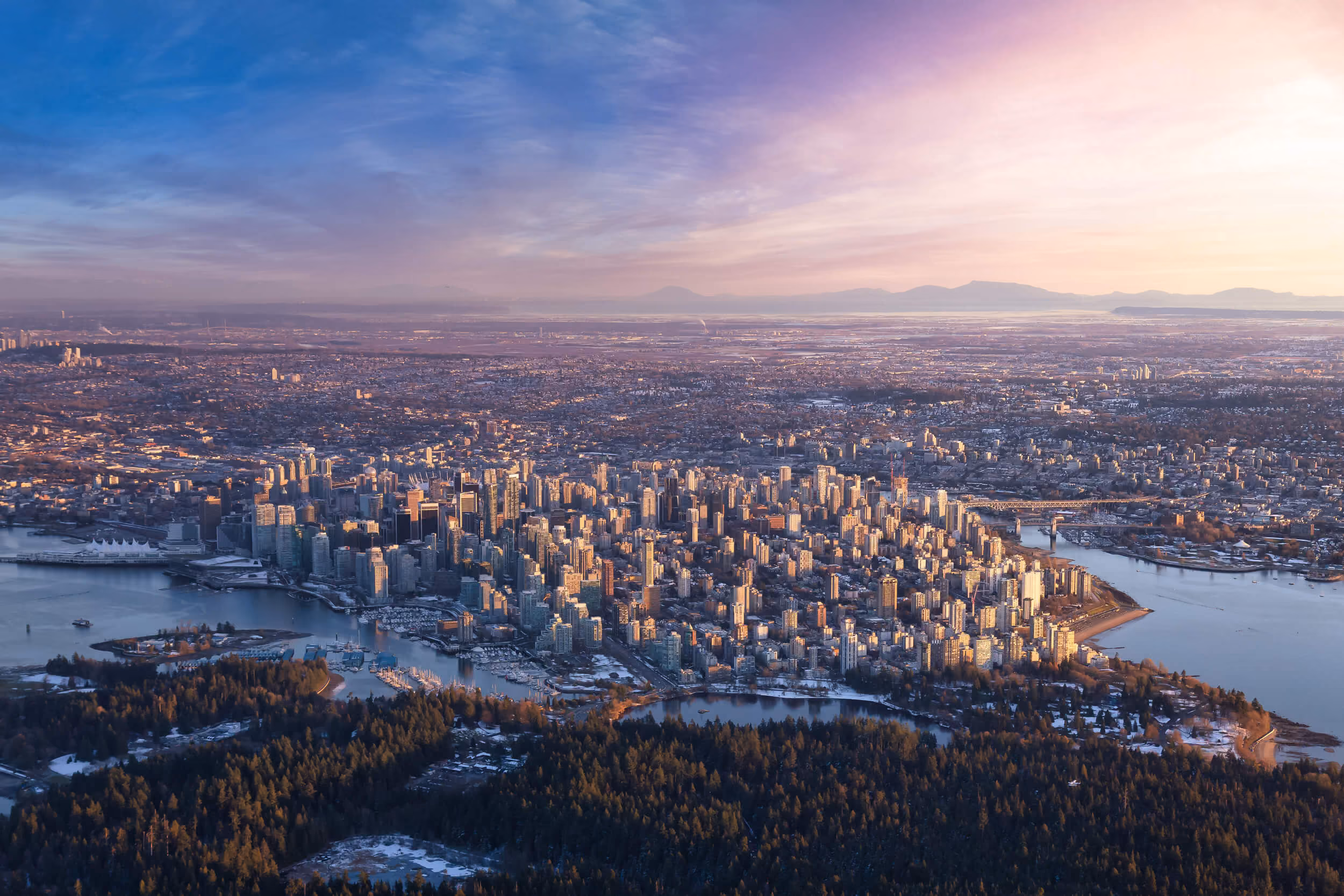 Areal view, looking south, of downtown Vancouver with the trees of Stanley Park in the foreground. 