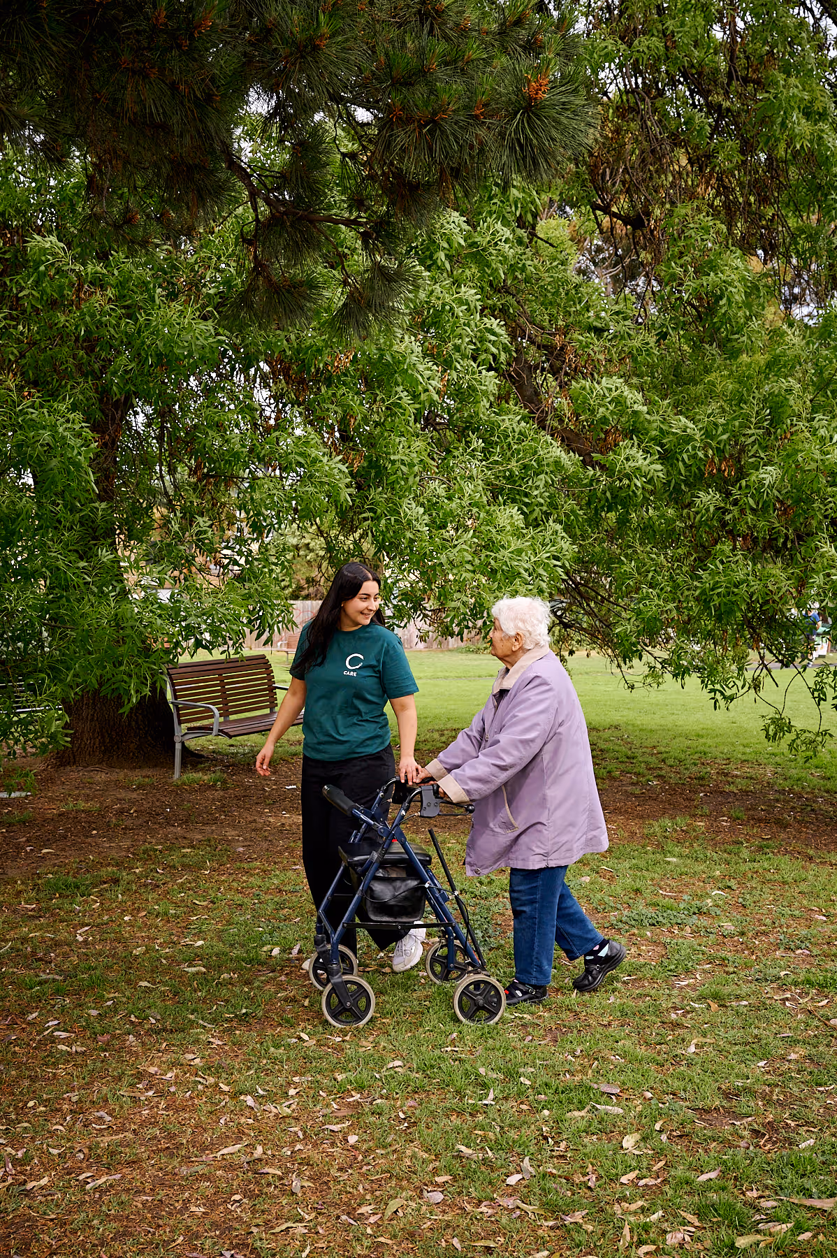 Woman helping elderly lady to walk in park