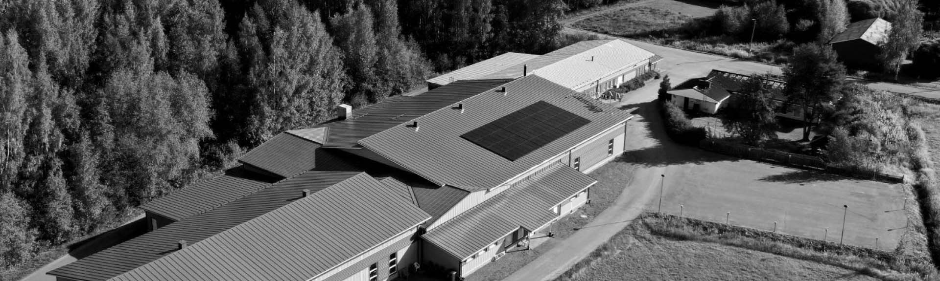 Ilmakuva suuresta rakennuksesta, jossa on useita harjakattoja, yhdellä katolla Ralos-aurinkopaneelit.