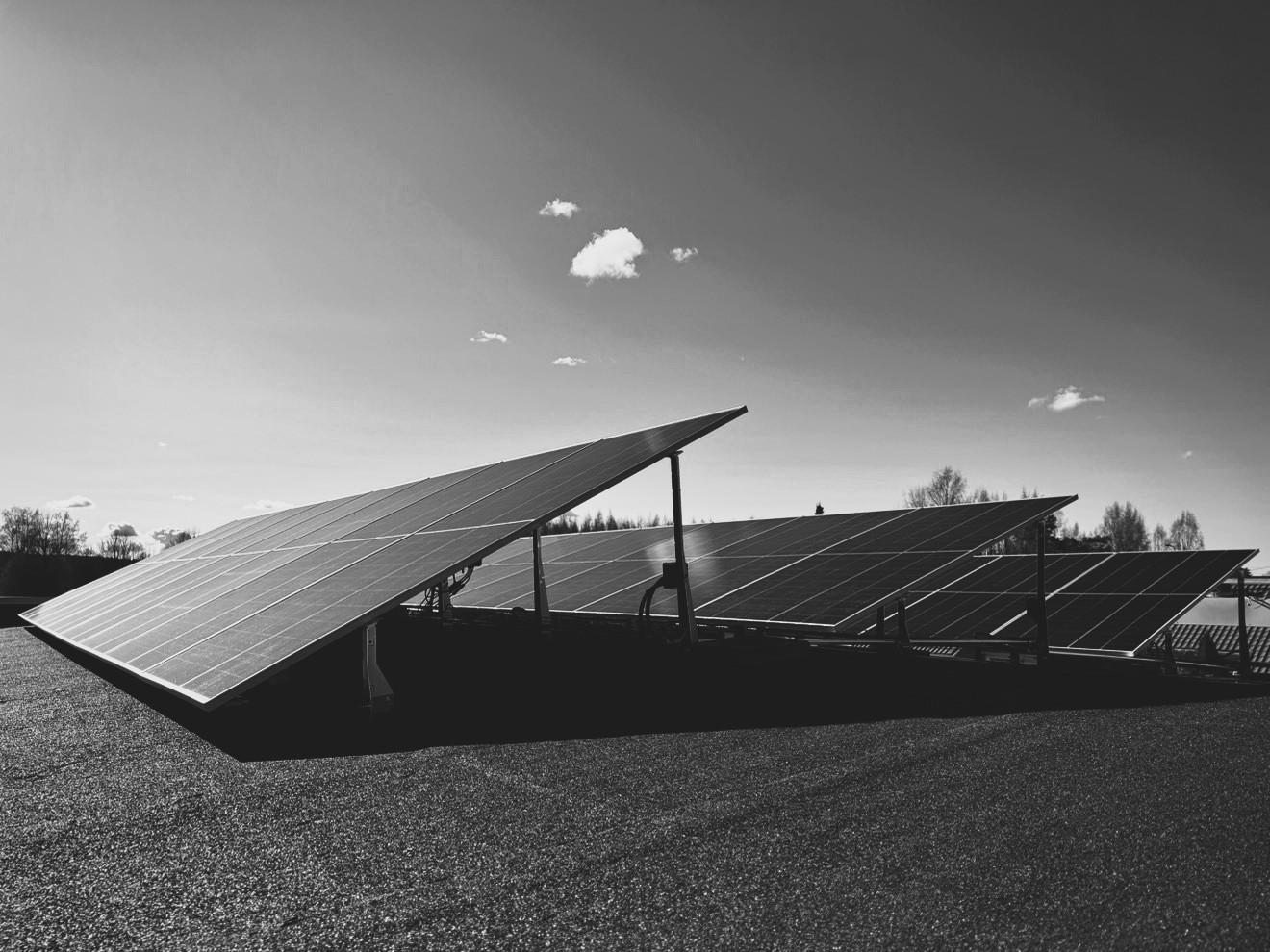 Ralos-aurinkopaneelit asennettuna kattopinnalle kirkkaan taivaan alla, muutamia pieniä pilviä.