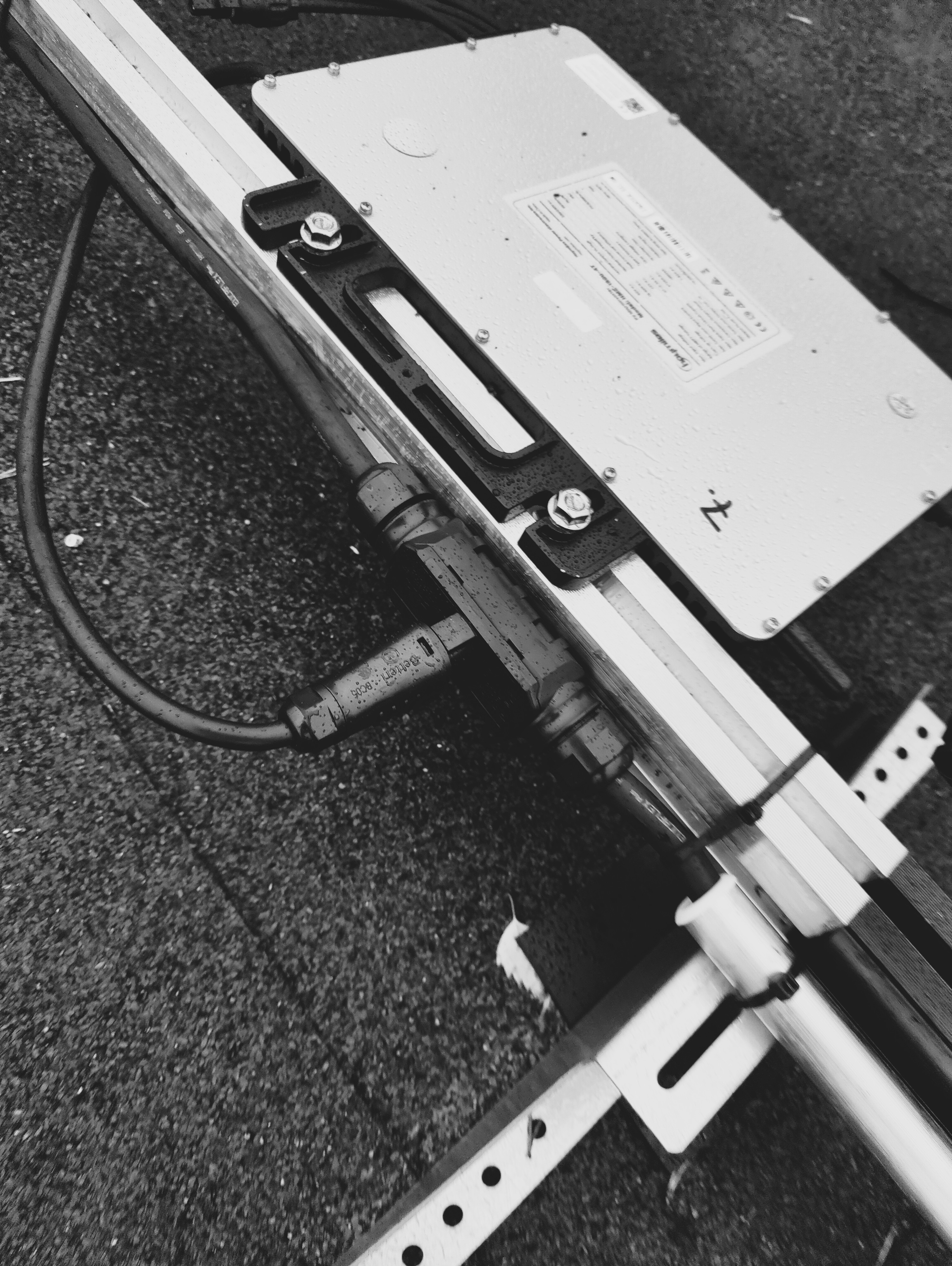 Lähikuva Ralos-sähkökaapeloinnista ja metallisesta kytkentärasiasta metallirungossa, pinnoilla sadepisaroita.