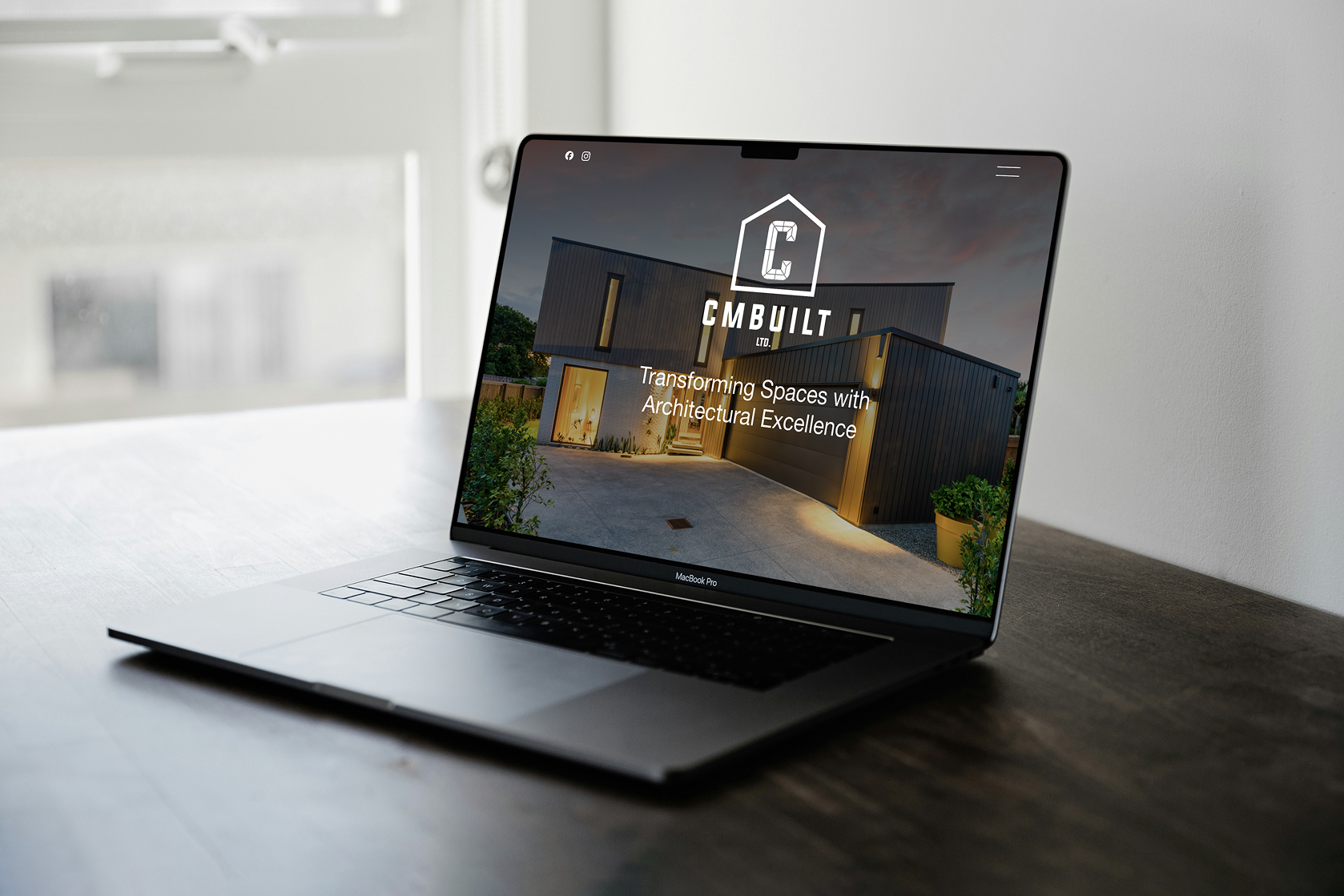 MacBook Pro laptop on a wooden table displaying a modern home with the logo and text 'CMBUILT LTD. Transforming Spaces with Architectural Excellence' on the screen.