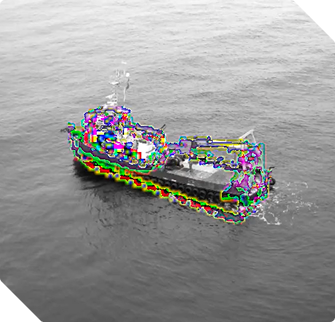 A small ship sailing on calm water, viewed from above.