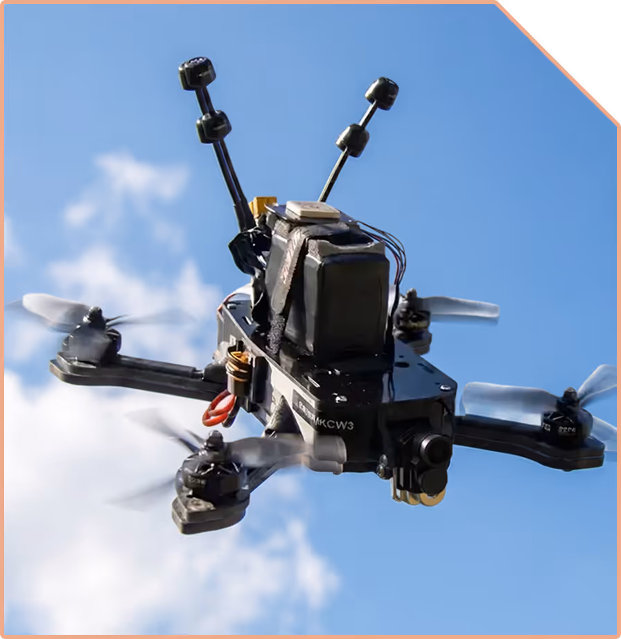 Close-up of a camera-equipped quadcopter drone flying against a blue sky with some clouds.