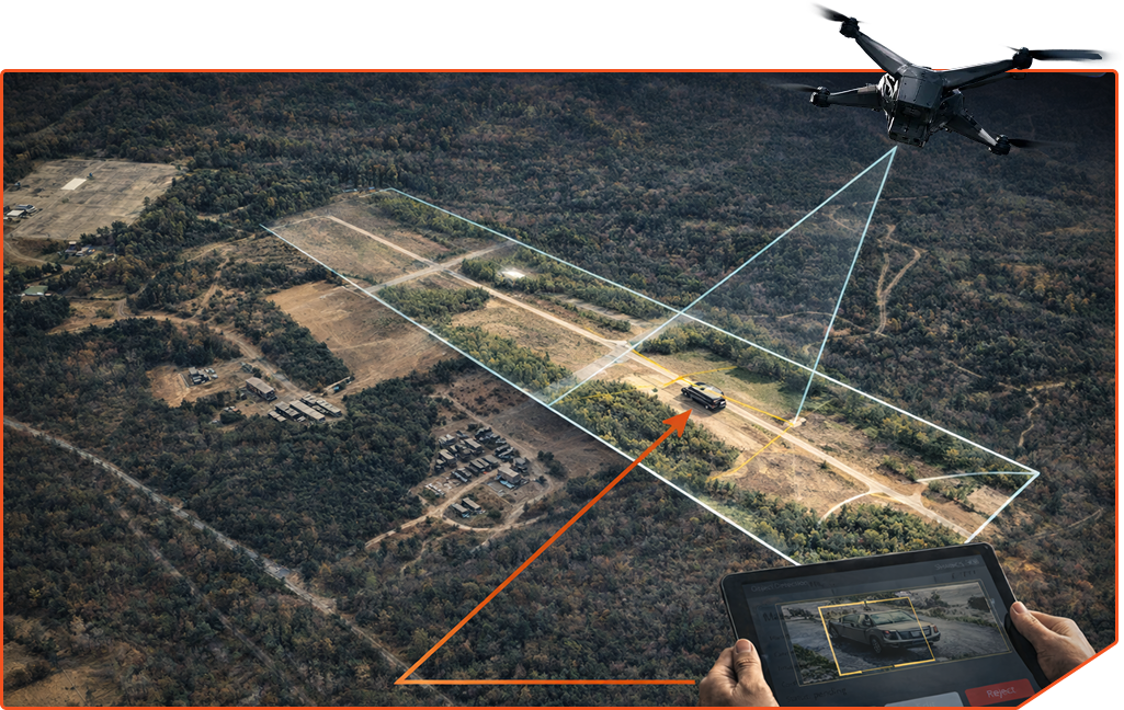 Drone flying over a forested area capturing a vehicle on a dirt road, with a tablet screen showing the vehicle detection and targeting.