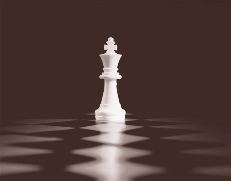 White king chess piece standing alone on a checkered chessboard with a dark background.