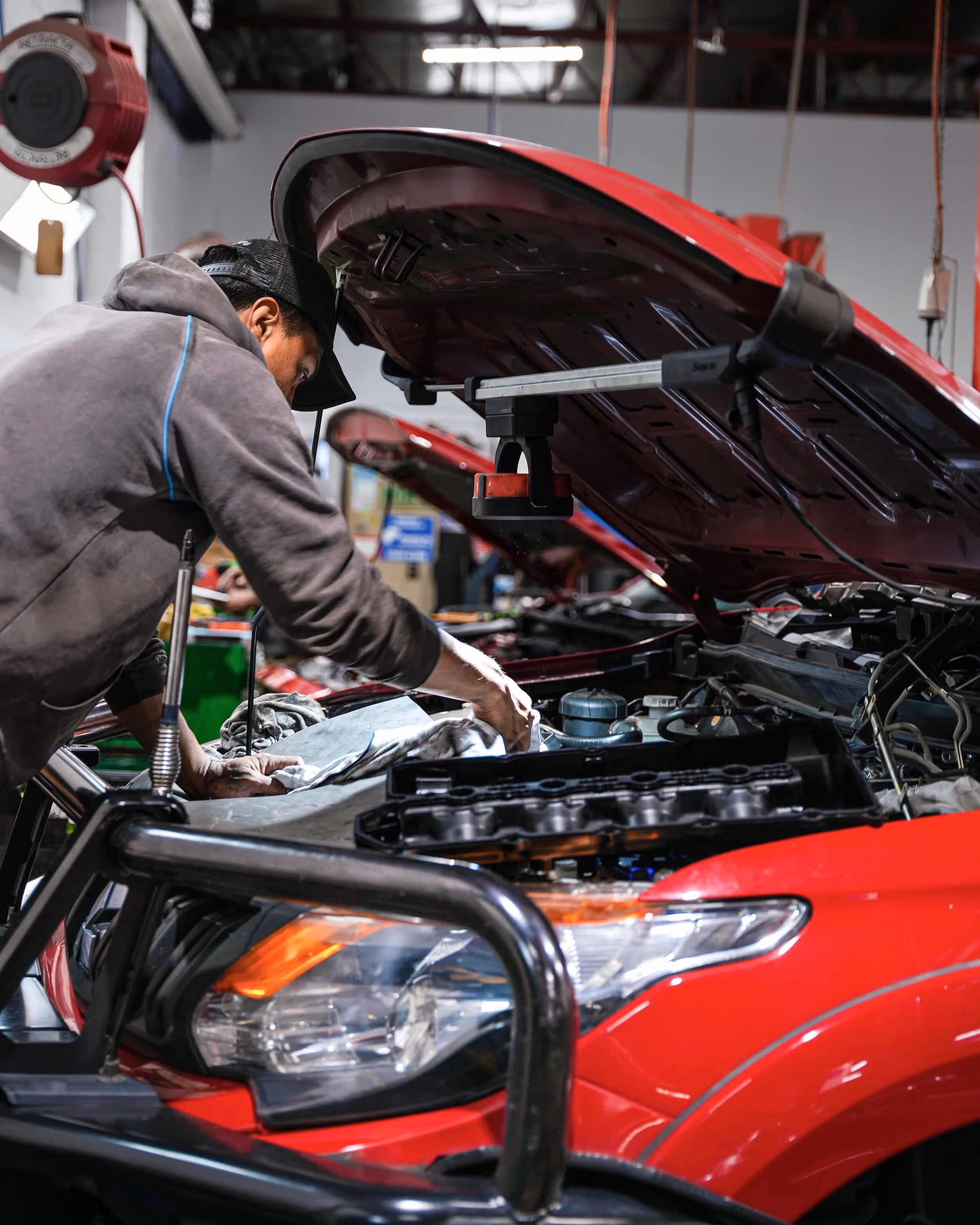 Pearson Automotive mechanic performing engine diagnostics and service on a red vehicle at the Milton workshop.