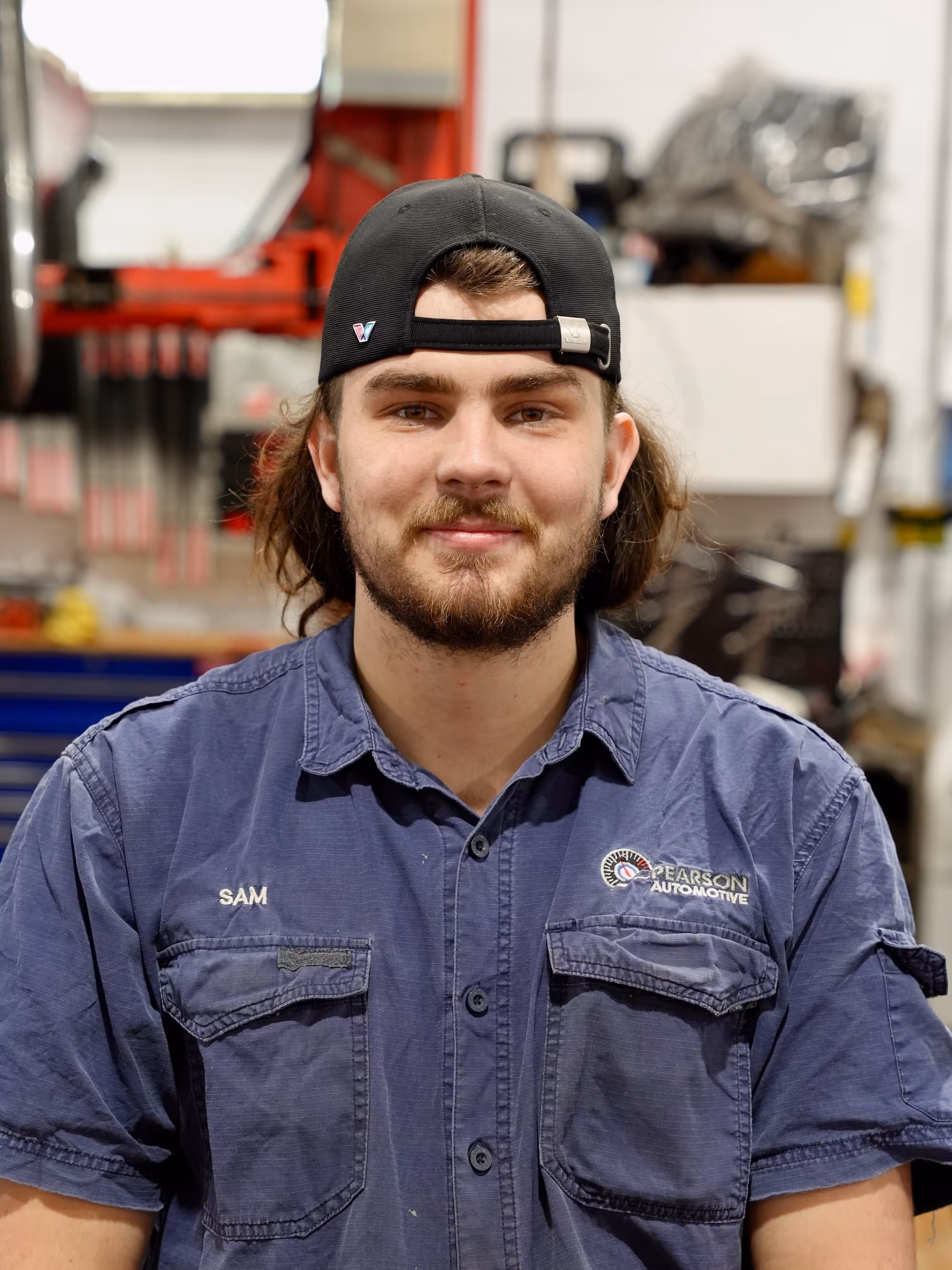 A member of the Pearson Automotive mechanic team wearing a grey branded hoodie in the workshop.