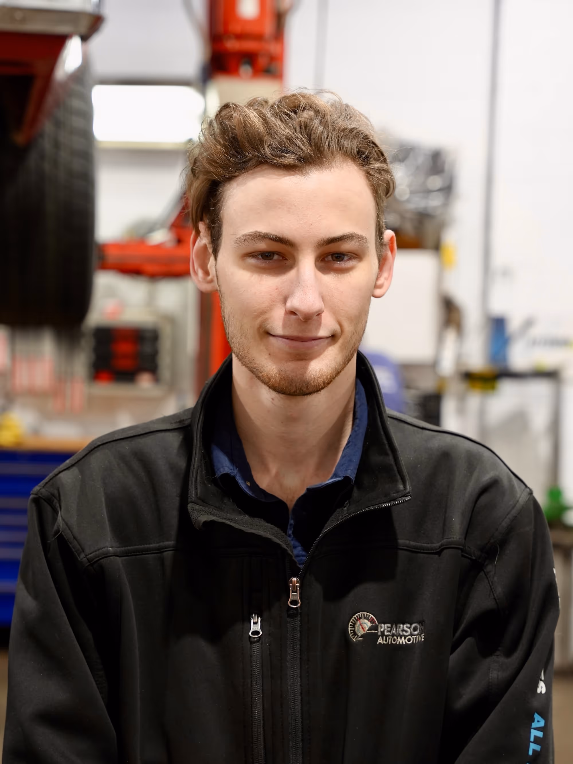 William, an automotive technician at Pearson Automotive in Milton, smiling and wearing a black work shirt.