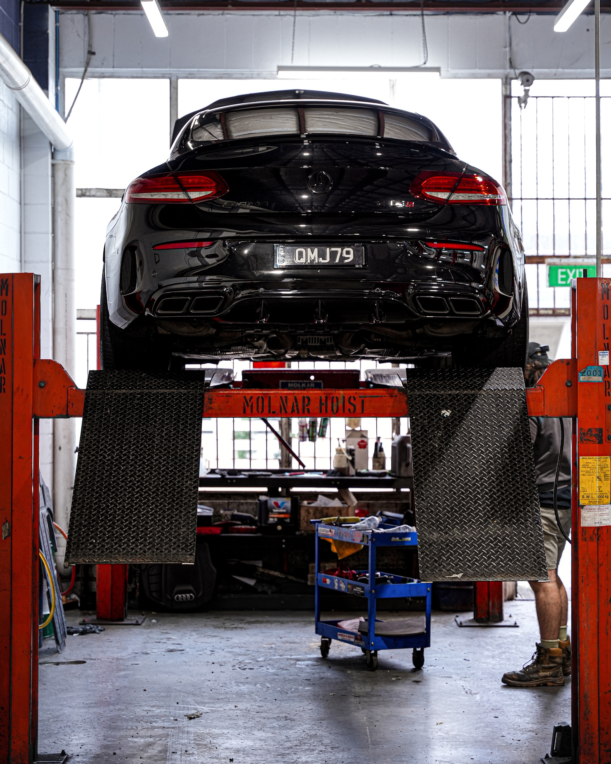 Rear view of a Mercedes AMG on the hoist at Pearson Automotive Milton for a performance exhaust inspection and system check.