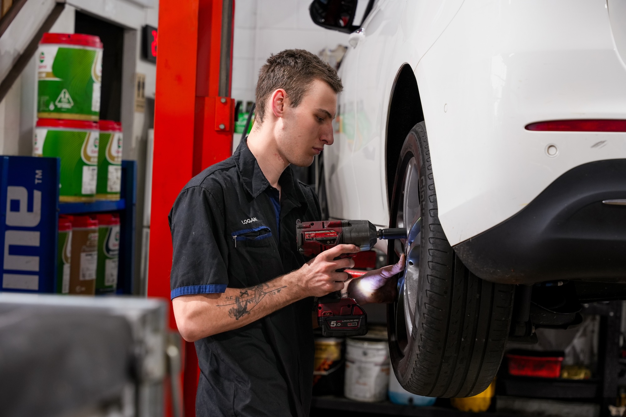 Inside the Pearson Automotive workshop in Milton, showing a mechanic servicing a vehicle on a hoist.