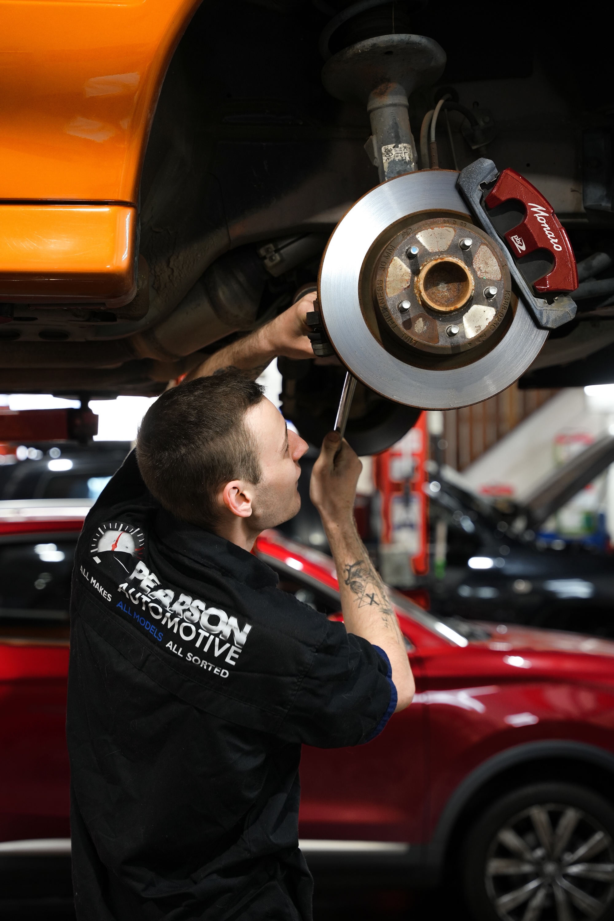 Senior mechanic using a precision torque wrench to ensure brake components and wheel nuts are tightened to manufacturer safety specifications.