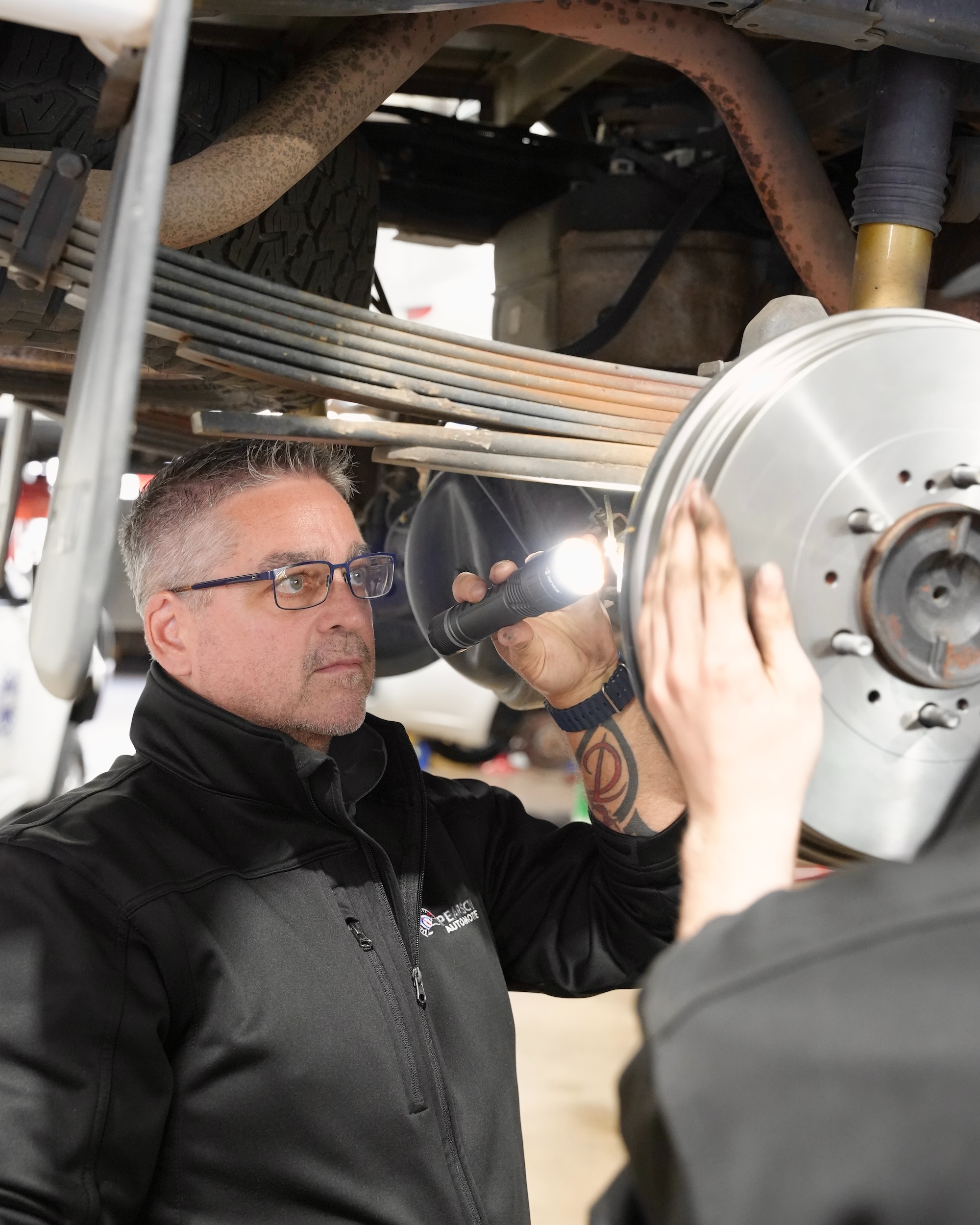 Pearson Automotive mechanic removing a vehicle wheel to inspect brake pads and rotors for wear in the Milton workshop.