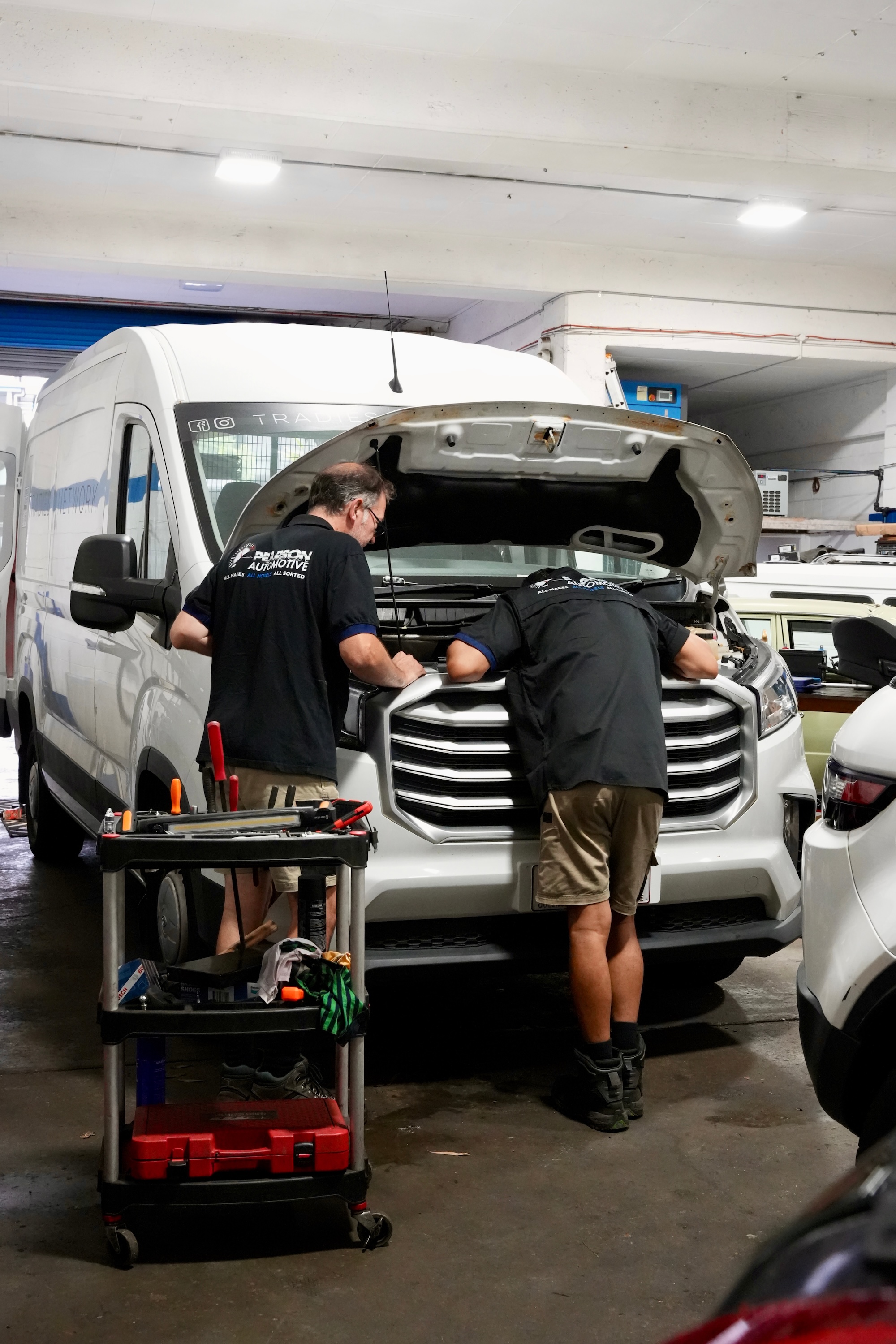 Two Pearson Automotive mechanics performing a comprehensive engine service on a commercial fleet van in Milton.