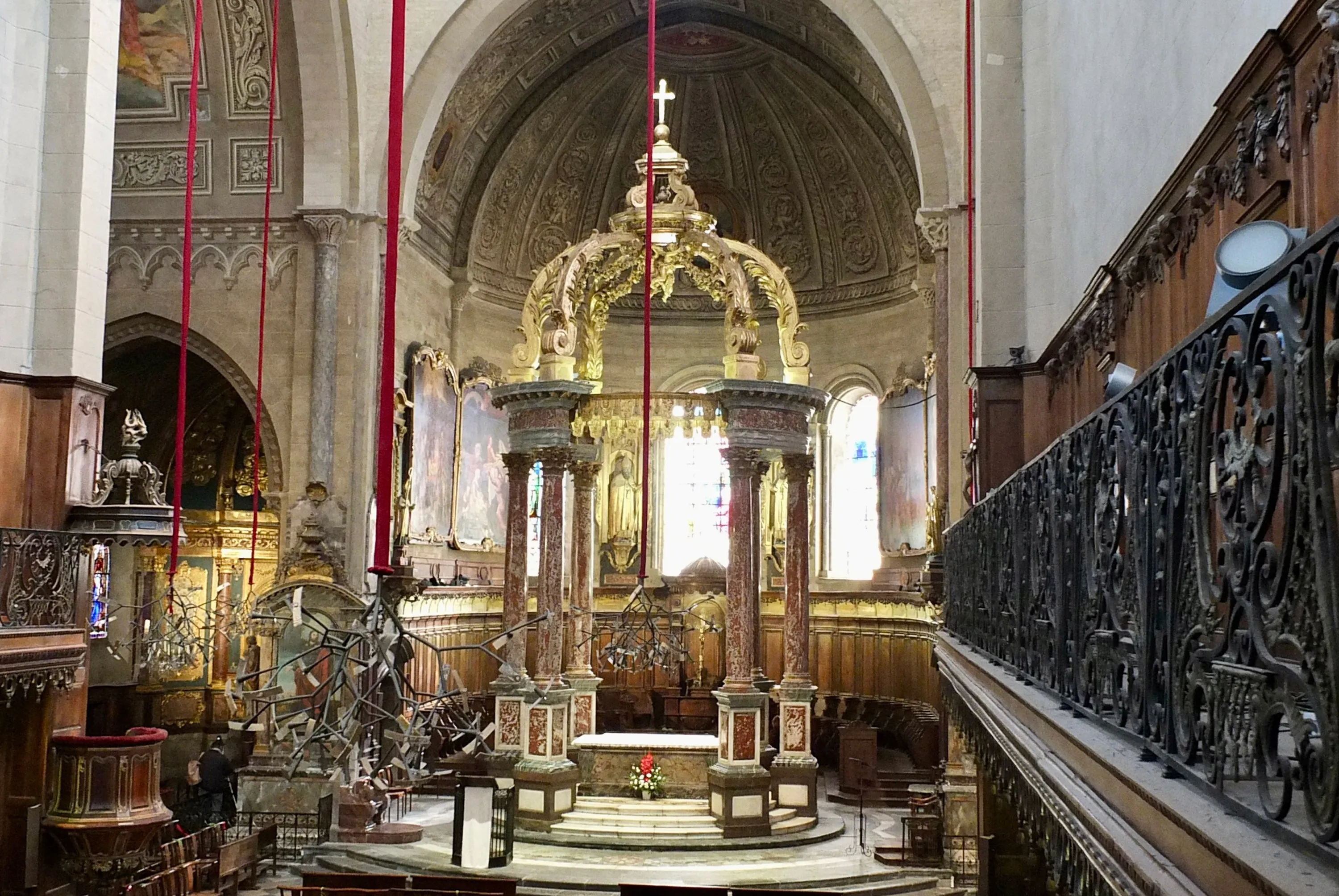 Intérieur d'une église avec baldaquin orné de colonnes rouges au-dessus de l'autel.