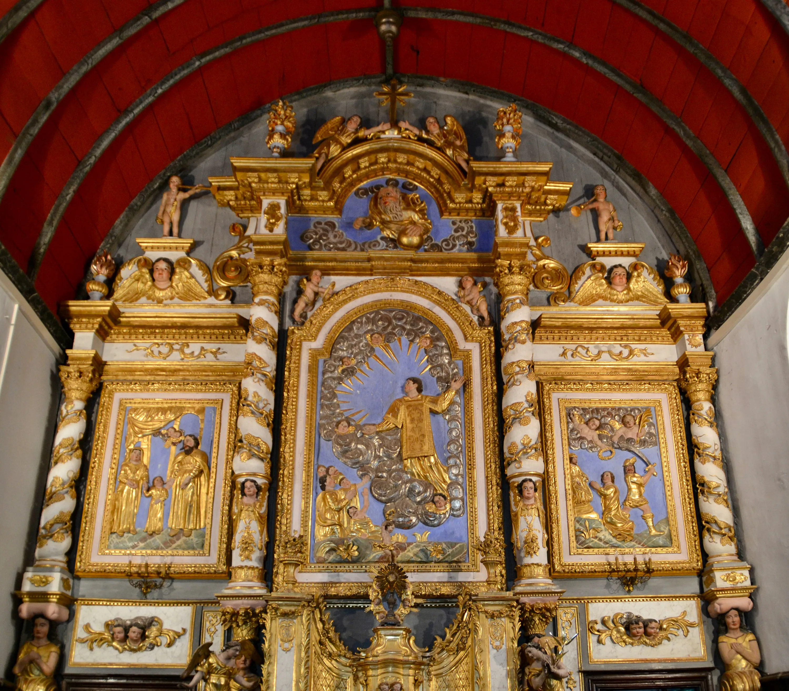 Retable doré avec des scènes bibliques et des anges sous une voûte rouge.
