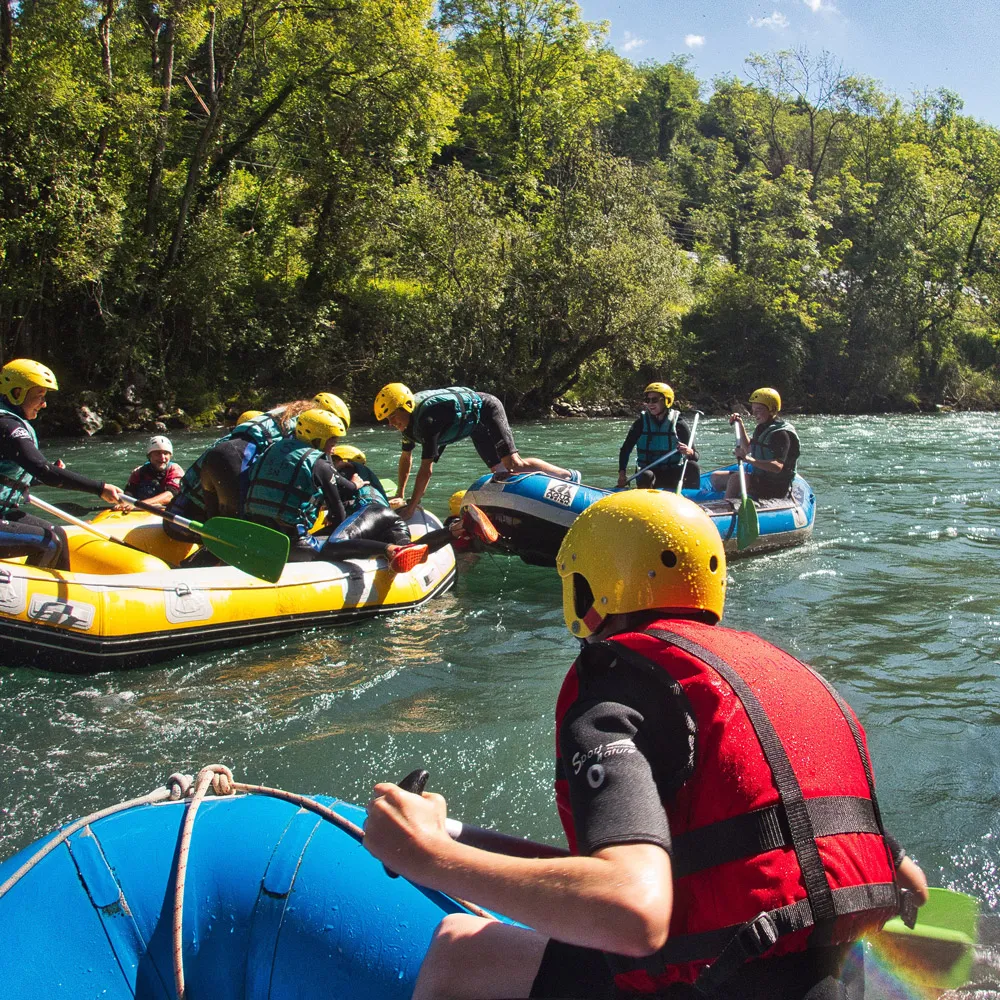 Personnes en gilets de sauvetage et casques jaunes sur des radeaux lors d'une activité de rafting sur une rivière