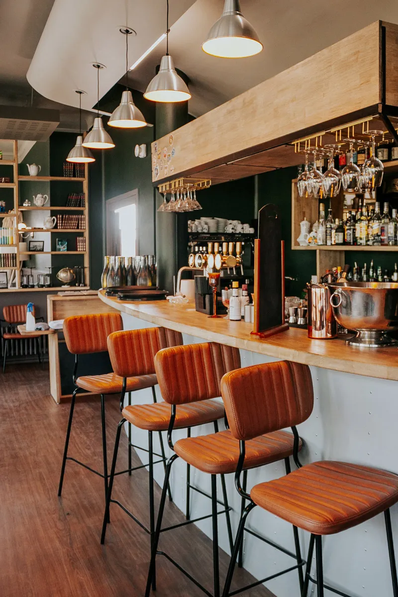 Intérieur de bar avec des tabourets en cuir orange alignés au comptoir en bois clair.