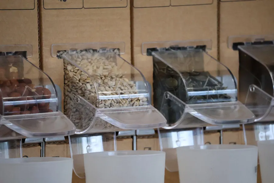Distributeurs en vrac en plastique avec différentes graines dans un magasin zéro déchet.