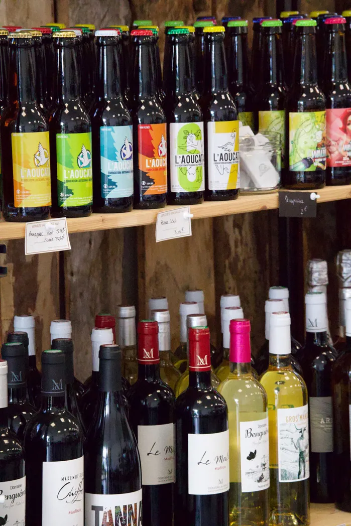 Bouteilles de bières artisanales L'Aoucai et de vins variés sur étagères en bois.