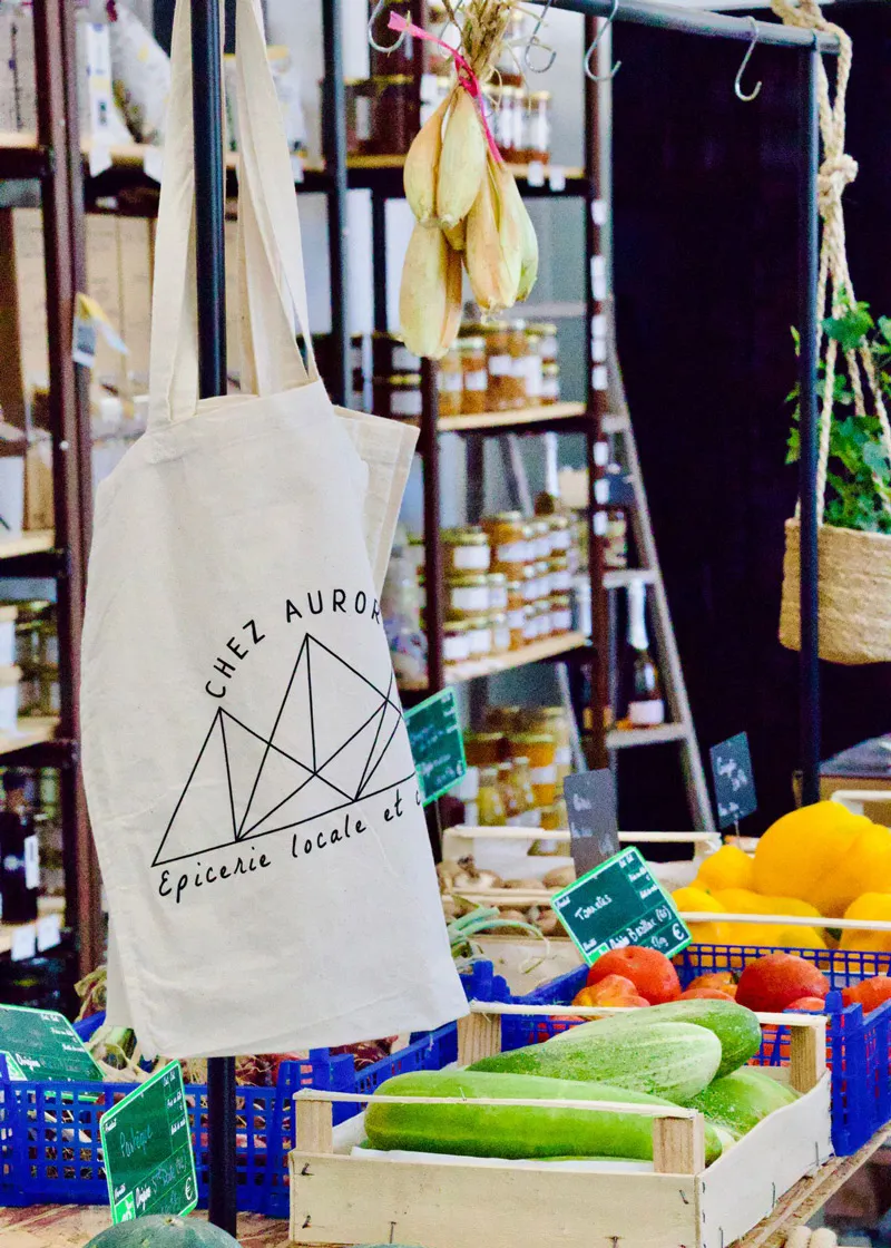 Sac en tissu suspendu avec légumes frais comme concombres, tomates et courges dans une épicerie locale.