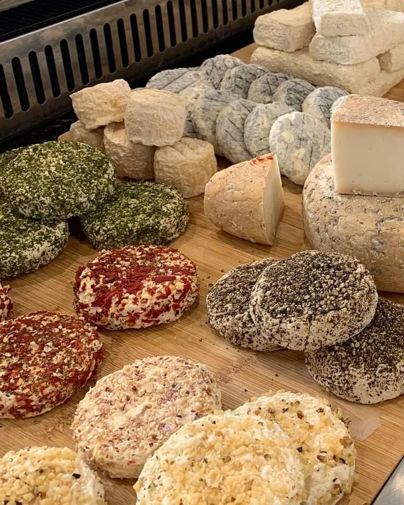 Assortiment de fromages artisanaux variés sur une planche en bois.