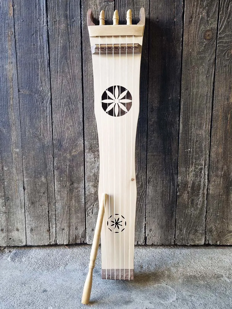 Instrument de musique traditionnel en bois avec cordes et deux motifs décoratifs circulaires sur fond de bois.