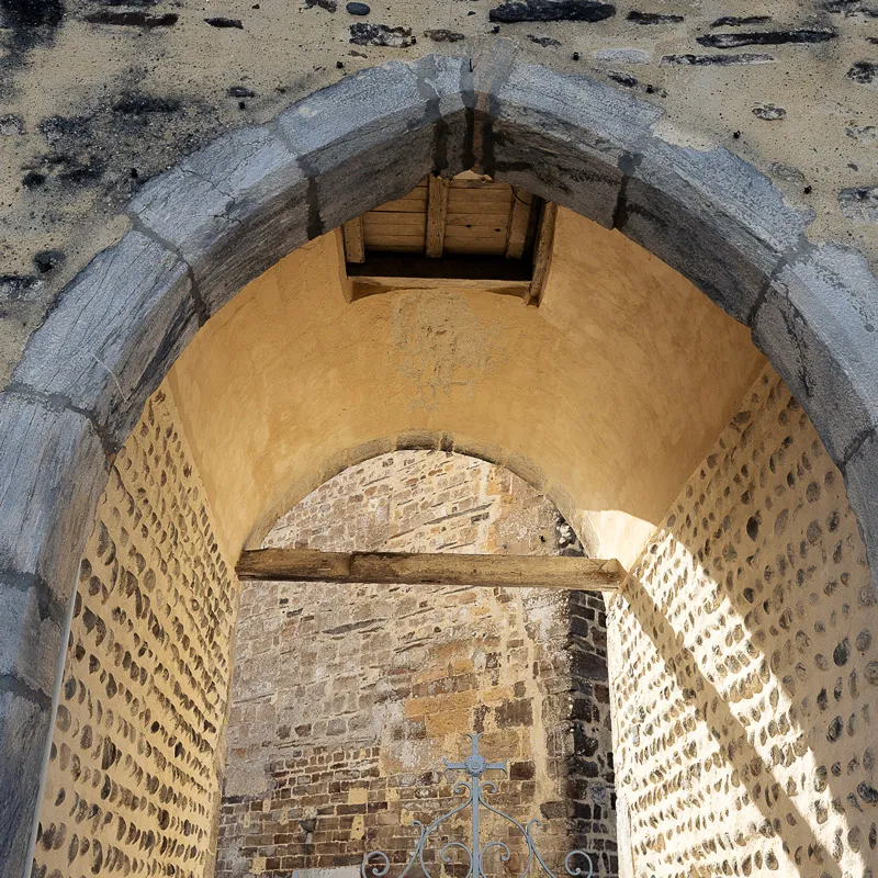 Arche en pierre avec mur en pierre et poutre en bois à l'intérieur éclairé par la lumière.