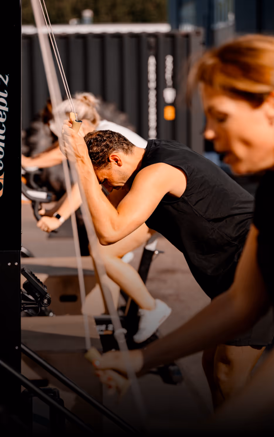 Group of people intensely exercising on ski erg machines in a gym setting.