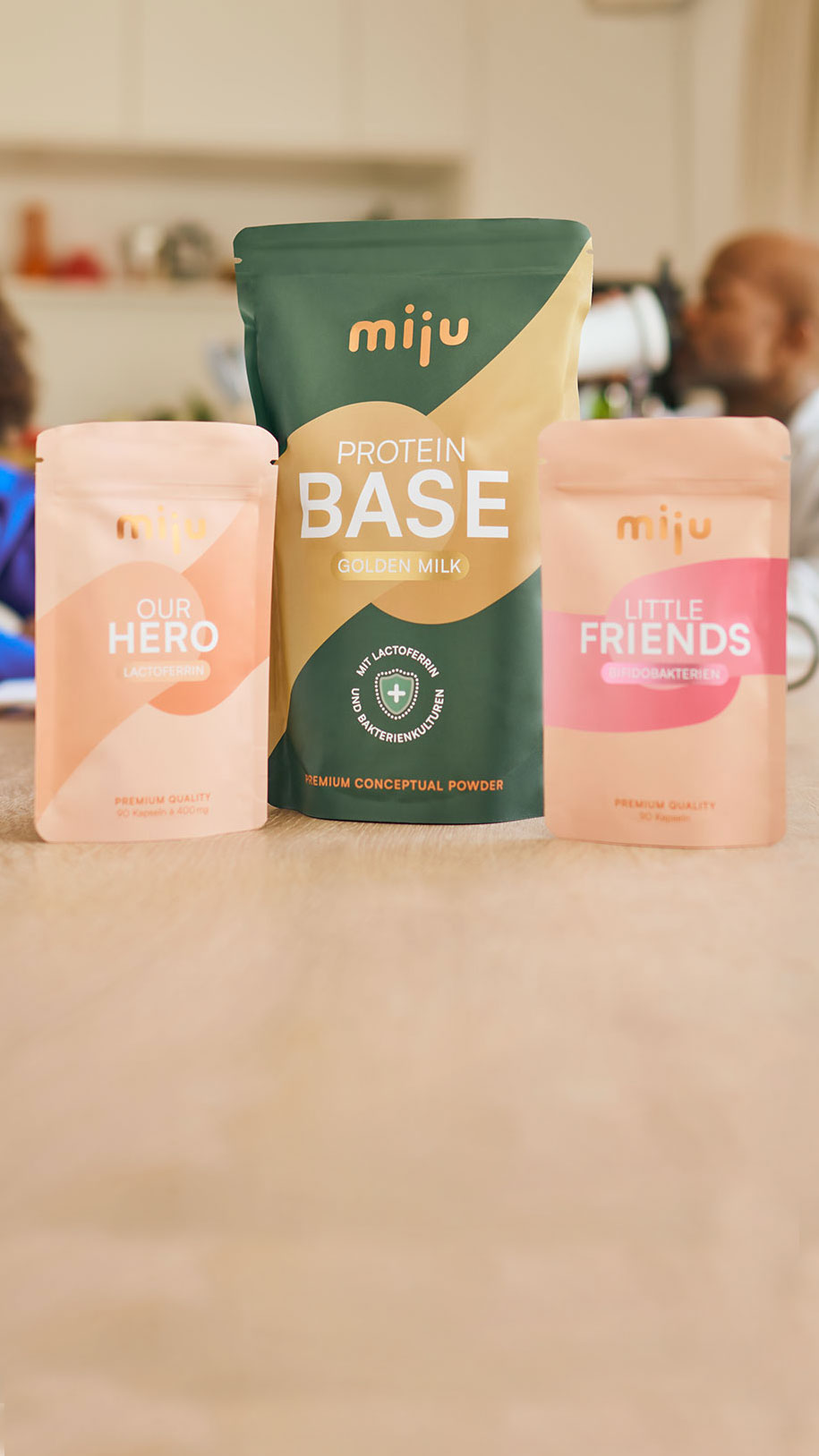 miju Lactoferrin, Bifidobakterien und Proteinpulver vor einer Familie im Alltag. Im Hintergrund trinkt ein Vater einen Proteinshake, während eine Großmutter gemeinsam mit ihrem Enkel lacht.