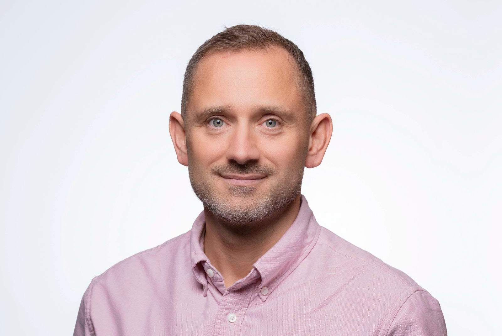 Dr Martin Lee smiling and wearing a pink shirt
