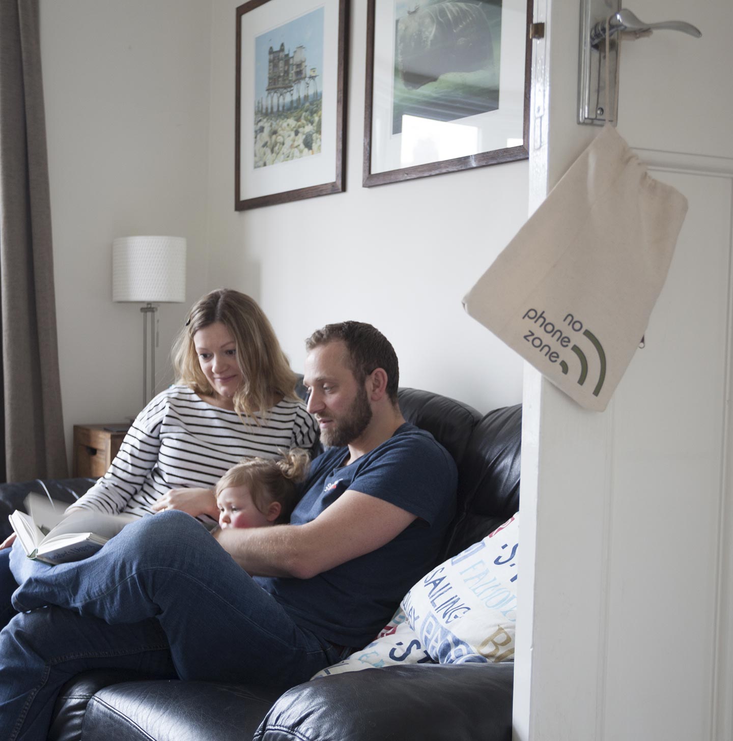 A family reading on a sofa without any devices in their hands