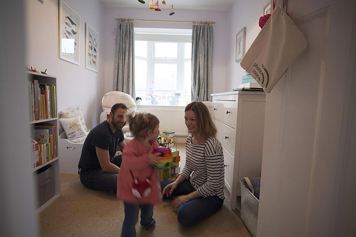 Parents sat on the floor playing with a toddler in a child's bedroom