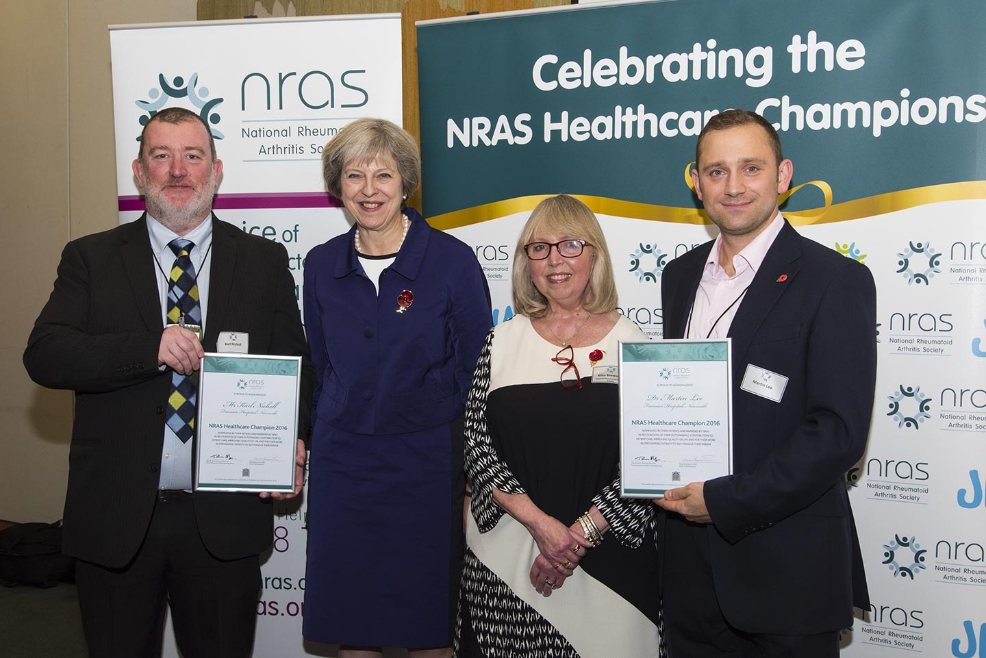Four people standing in front of NRAS banners as two accept awards