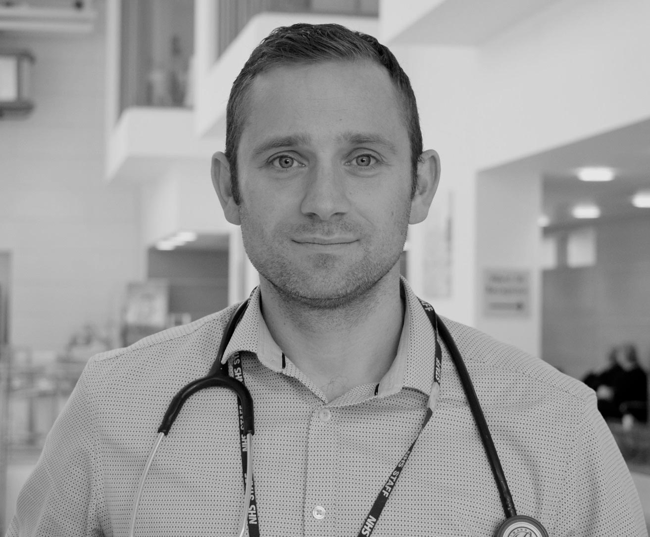 A rheumatologist in a hospital with a stethoscope around his neck